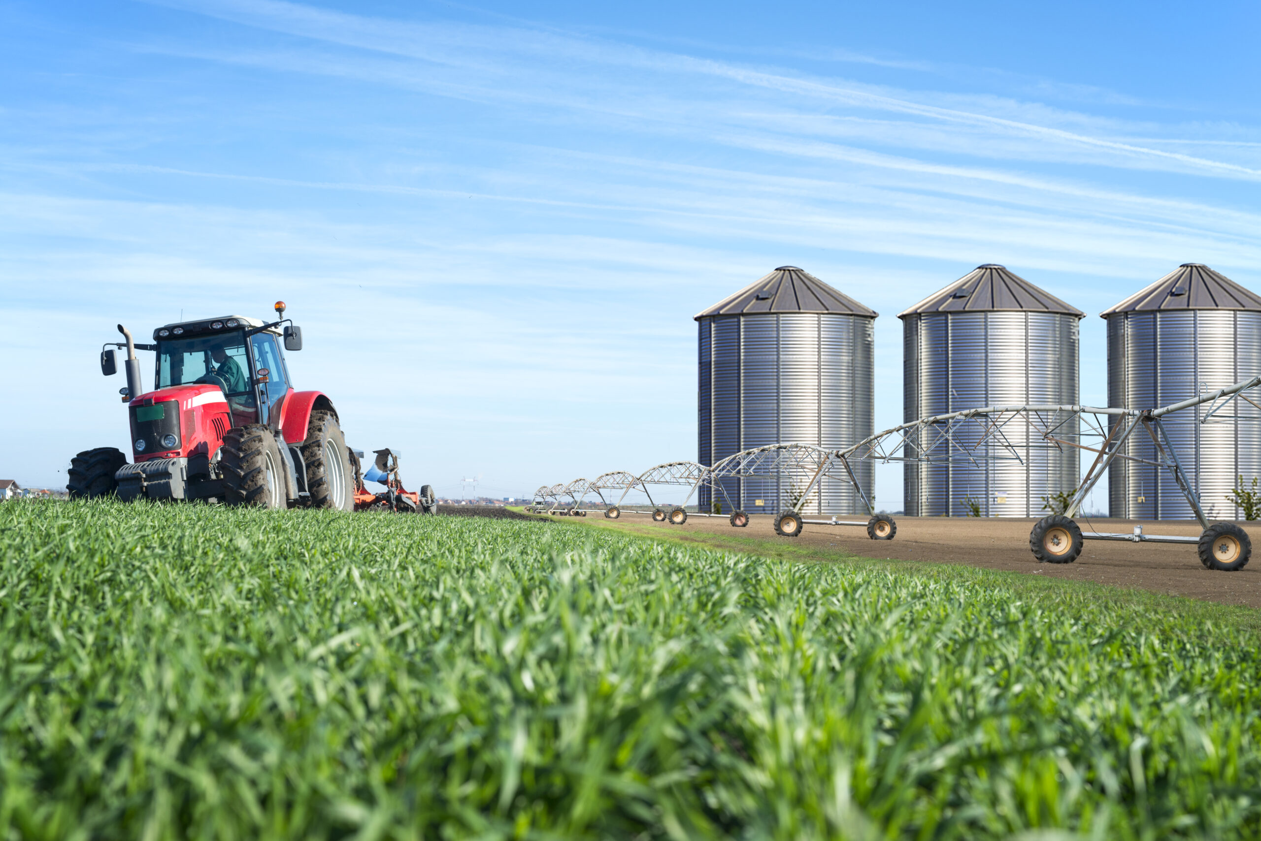 agriculture and food production concept with tractor machine silos and irrigation system.